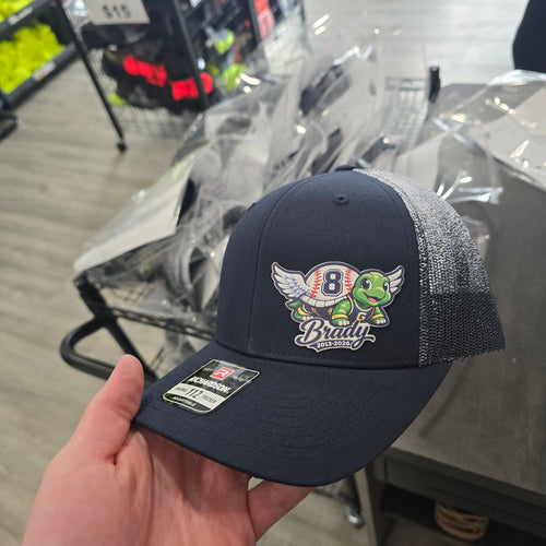 Navy blue cap with a turtle graphic and number 8 held in a hand, with a store setting in the background.